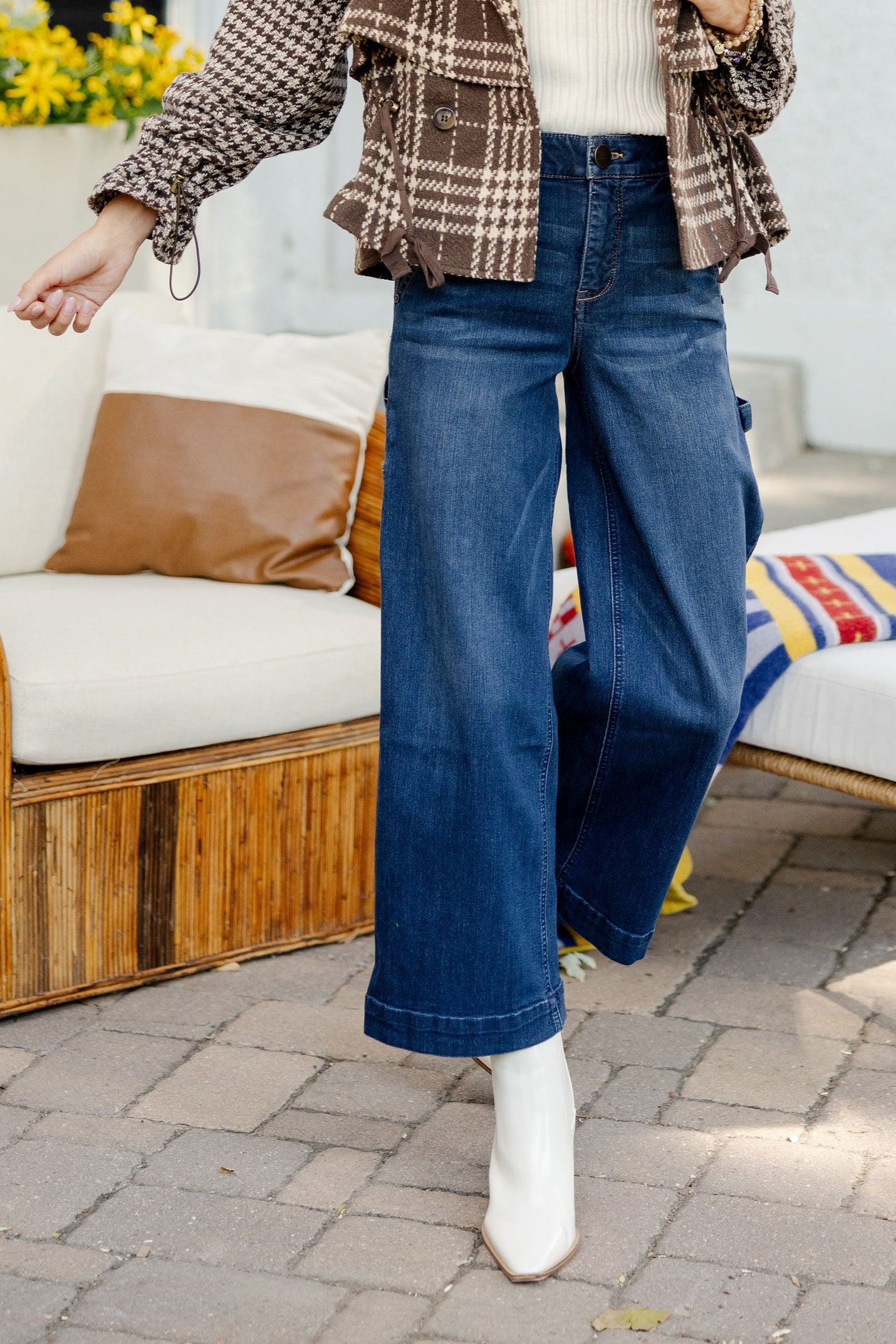 Woman standing outdoors on a patio with furniture and plants.