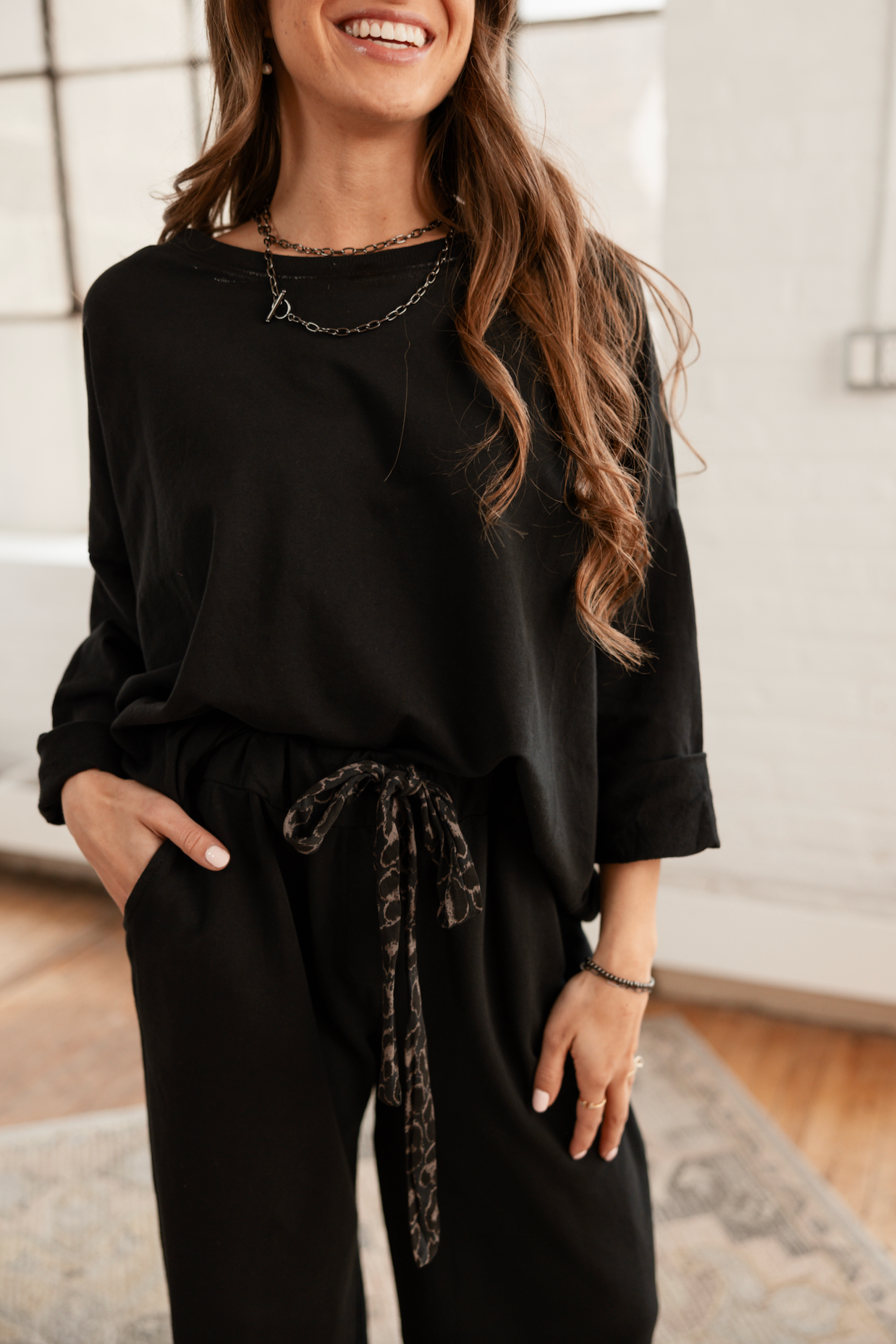Woman wearing a black outfit in a room with large windows.